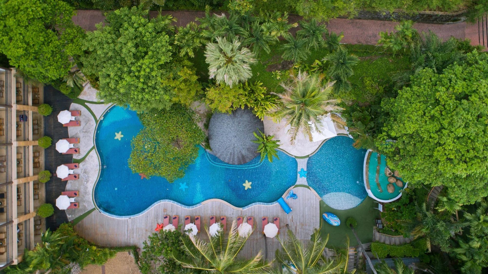 A turquoise swimming pool surrounded by tropical gardens at the resort